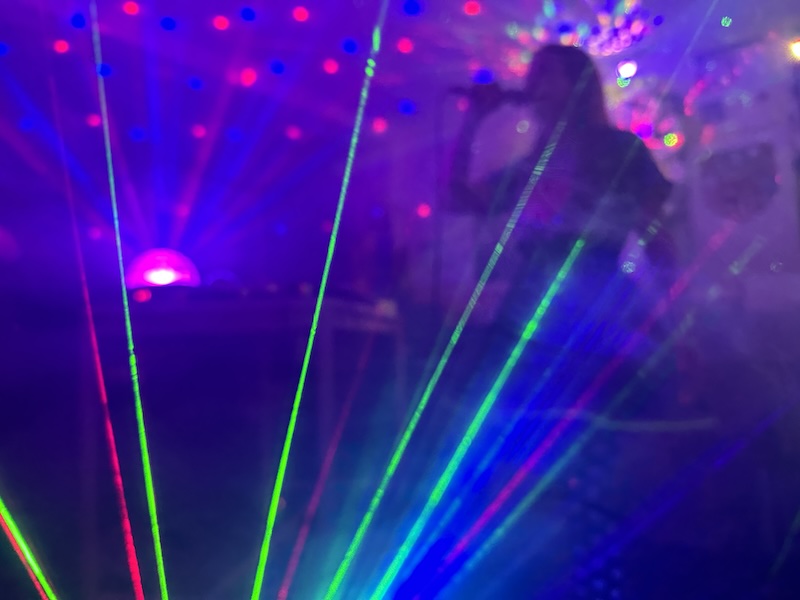 A silhouette of a woman singing. Lasers in the foreground.