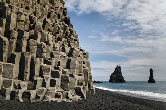 Basalt columns and sea stacks at Reynisfjara black sand beach near Vík in South Iceland, one of the country’s most dramatic coastal landscapes.