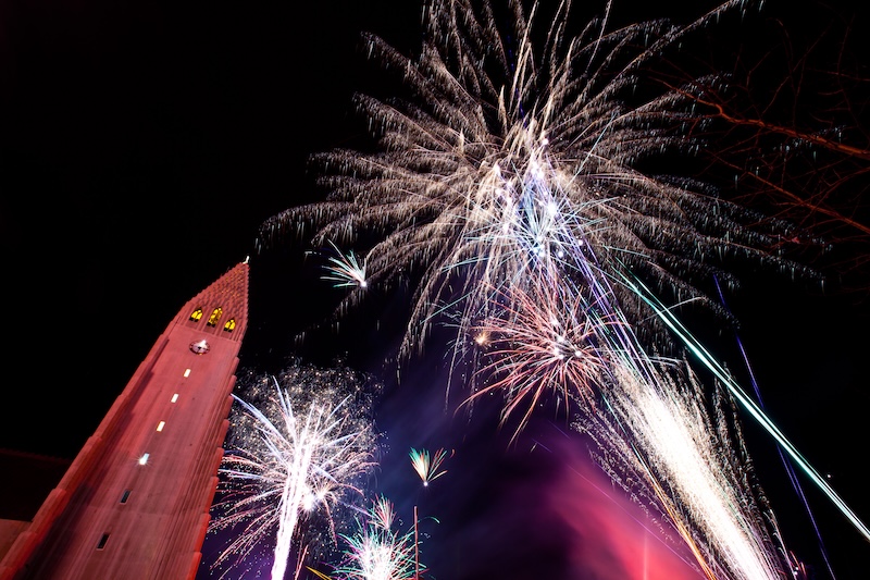 Explosions of brightly colored fireworks light up the night sky over the tower of Hallgrímskirkja church in Reykjavík, Iceland, during the massive New Year's Eve celebrations.