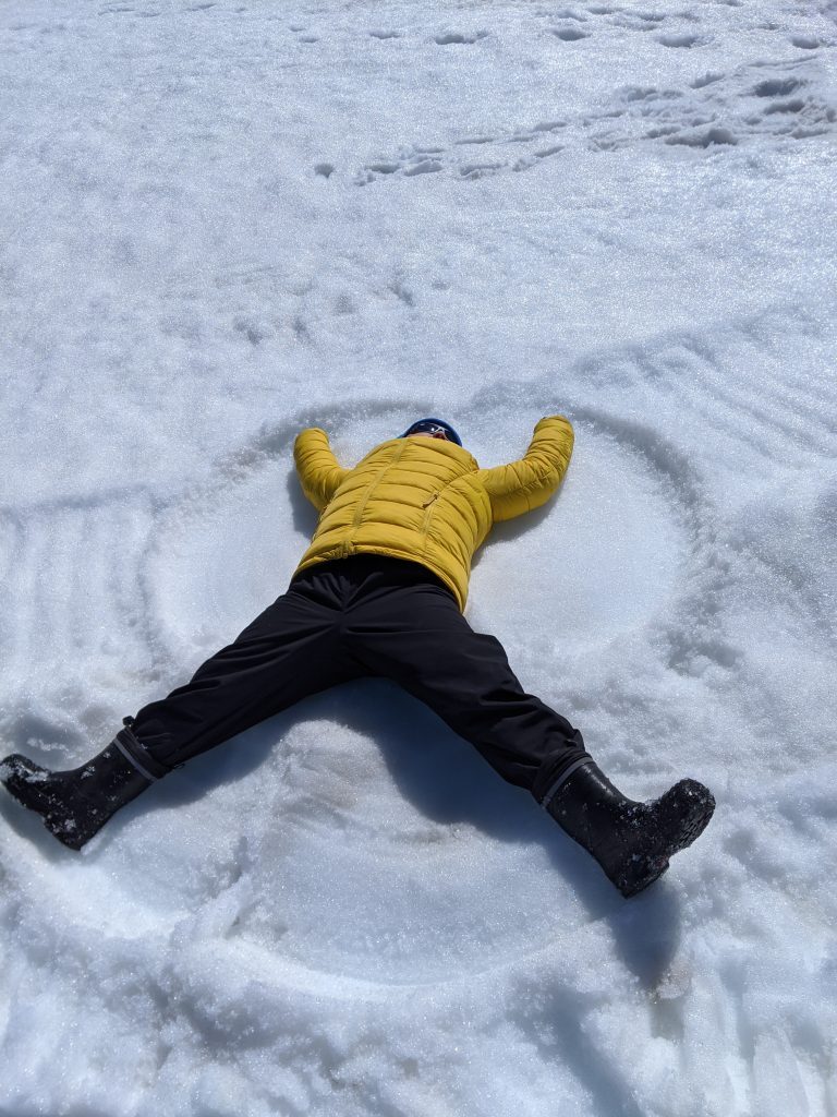 Boy creating a snow angel on a glacier in Iceland.