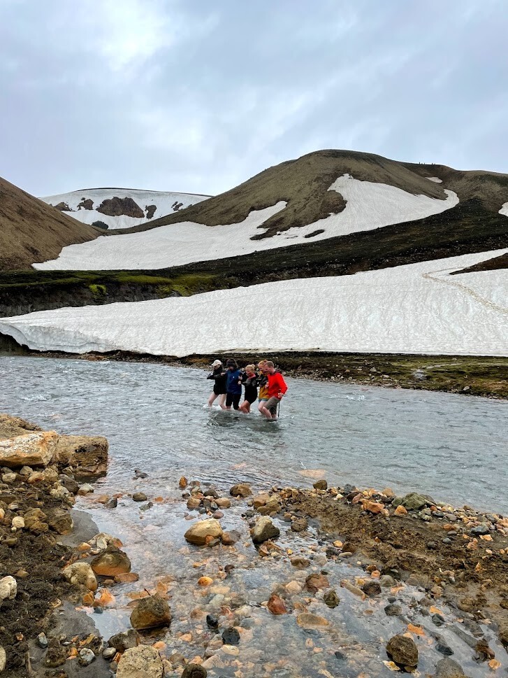 A group of people wading across a stream in the Icelandic highlands, right next to Grænahryggur ridge.
