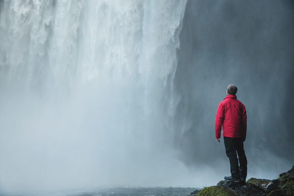 Man at Skógafoss waterfall in Iceland. Things to in Iceland includes chasing waterfalls