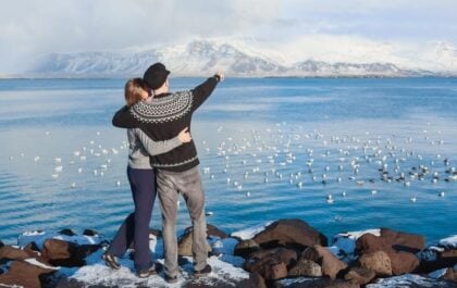 Couple enjoying a perfect day in Reykjavik with Mount Esja and the bay in the background