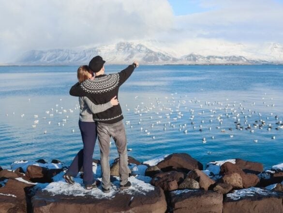 Couple enjoying a perfect day in Reykjavik with Mount Esja and the bay in the background
