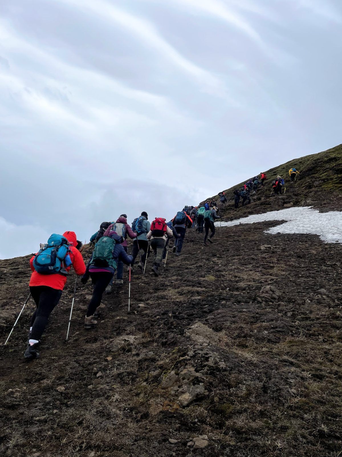 People are hiking up a steep slope in the Icelandic highlands.
