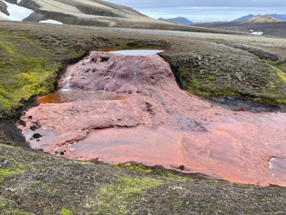 Water streams into the red riverbed at Rauðauga, the source of the Rauðukvísl river in the Icelandic highlands.