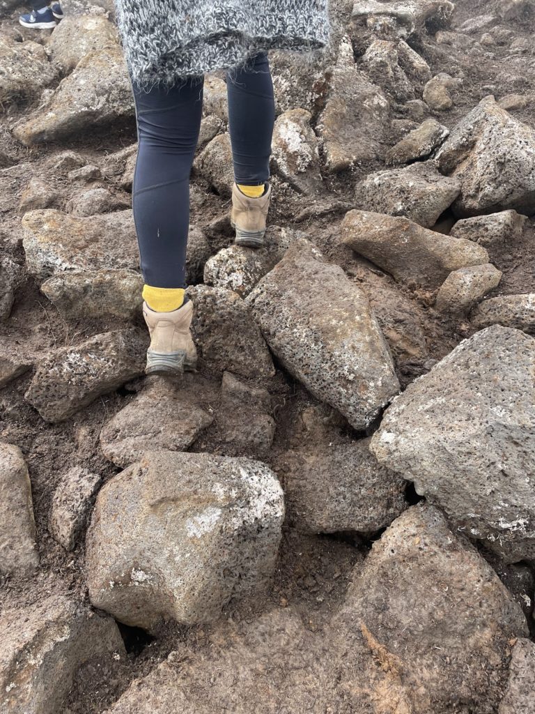 A young woman walks over rocky ground on her way to the volcano erupting in Iceland in 2022