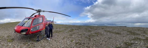People on the top of Mt. Esja in Iceland with a helicopter.