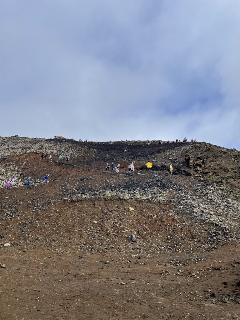 People climbing up a steep hill on their way to the volcano erupting on the Reykjanes peninsula in Iceland in 2022.