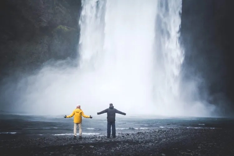 Two people in front of Seljalandsfoss waterfall in Iceland.