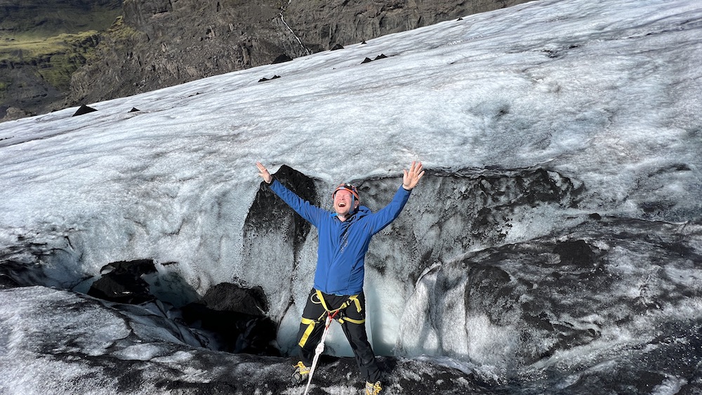 Silly man leans over a crevasse on Sólheimajökull glacier in the south of Iceland.