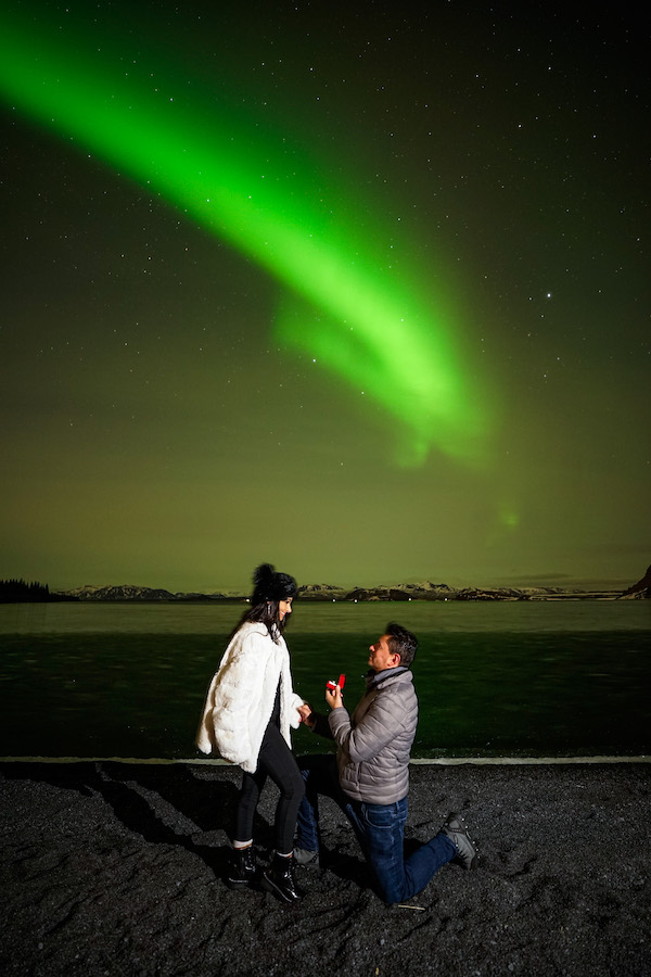 A man proposes to a woman in front of northern lights in Iceland.