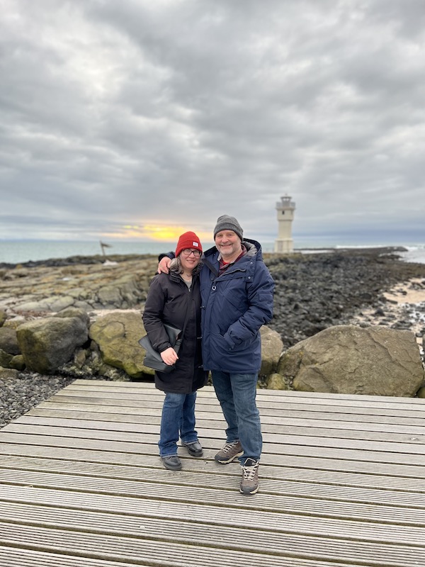A couple stand in front of the lighthouse in Akranes in Iceland.