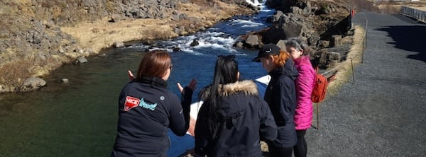 A tour guide with people at a river in Iceland.