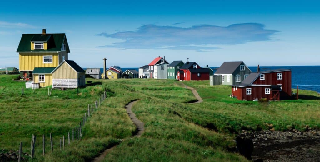 A summer day in the Icelandic island of Flatey. The photo shows a clear blue sky and colored old houses.