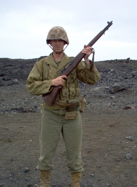 A man dressed like a US marine in the battle of Iwo Jima. He holds a Garand M1 rifle.