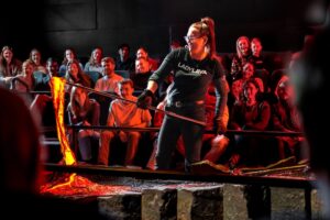 Presenter at the Icelandic Lava Show in Reykjavík demonstrating live molten lava flow to an audience, showcasing real volcanic activity in a safe, educational indoor setting