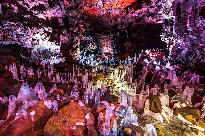 Inside Raufarhólshellir lava tunnel in Iceland, featuring stunning natural ice stalagmites and vibrant lava rock walls — a captivating underground experience featured among the best tours in Iceland 2025.
