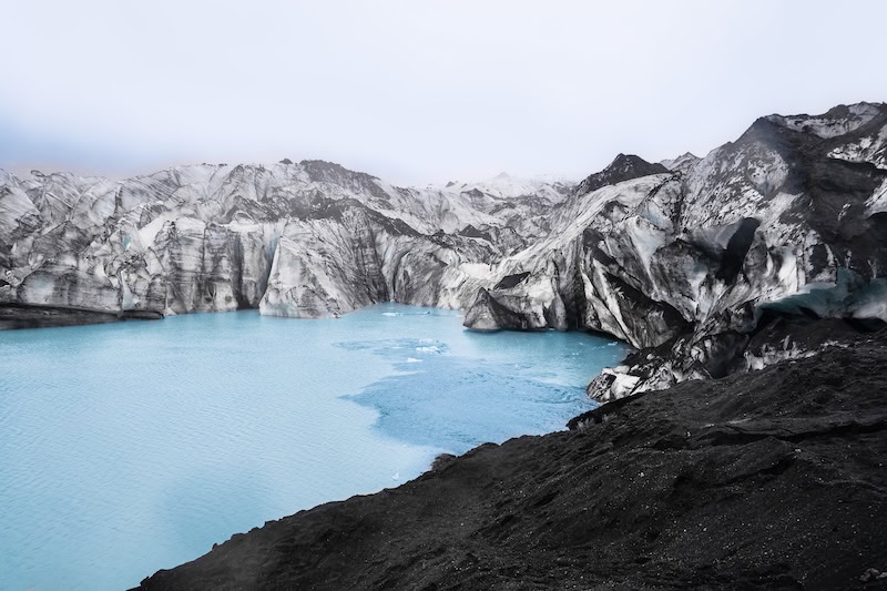 A striking view of Sólheimajökull glacier in South Iceland, featuring vibrant blue meltwater and rugged ice formations — a highlight on many of the best tours in Iceland 2025 for nature lovers and adventure seekers.