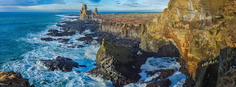 Panoramic view of Lóndrangar sea cliffs on the Snæfellsnes Peninsula, where dramatic basalt formations meet the roaring Atlantic