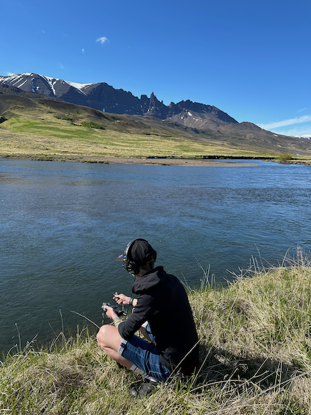 Kaśka Paluch recording natural river sounds in the Icelandic countryside with mountains in the background. Part of her Noise From Iceland soundscape project.