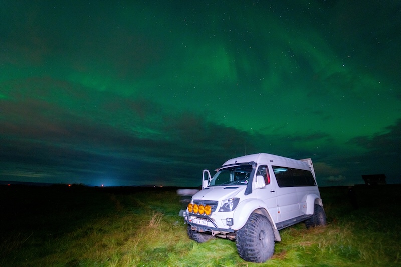 A superjeep is shown underneath the northern lights in Iceland.