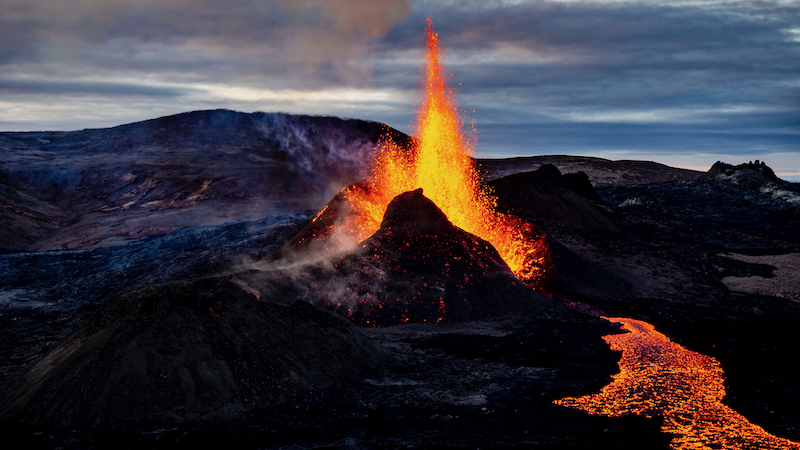 Eruption at Fagradalsfjall Volcano in Iceland, with flowing lava, volcanic craters, and smoke rising from the eruption site. A dramatic example of Iceland's volcanic activity.