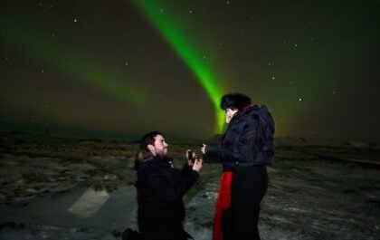 A man proposes to a woman under the aurora in Iceland. They are on a Northern Lights Tours with Gravel Travel.
