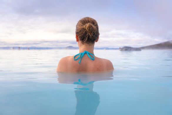 Woman relaxing in the Blue Lagoon geothermal spa in Iceland, surrounded by steam and volcanic landscapes.