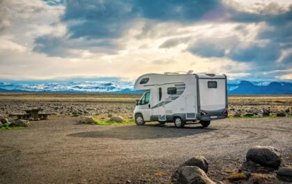 Camper van parked in a scenic Icelandic landscape with snow-capped mountains in the distance, illustrating a stop along the Ultimate Ring Road Guide route.