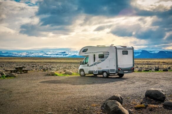 Camper van parked in a scenic Icelandic landscape with snow-capped mountains in the distance, illustrating a stop along the Ultimate Ring Road Guide route.