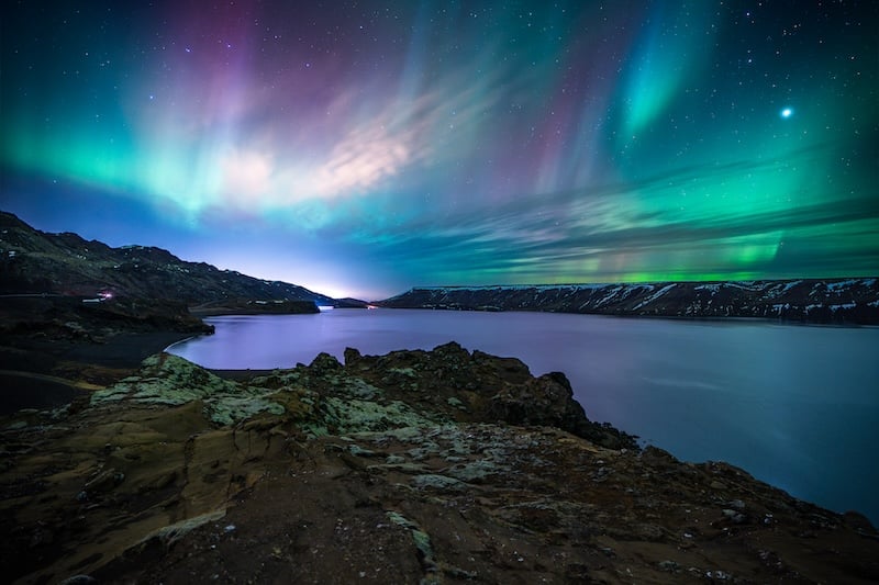 Northern lights aurora borealis over Iceland lake photographed by Rico de Jong - green and purple colors.