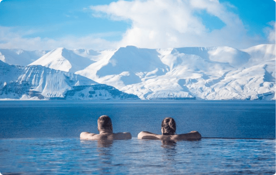 Couple relaxing in the GeoSea geothermal baths in Húsavík, overlooking the Arctic Ocean along the Diamond Circle on an Iceland road trip vacation.