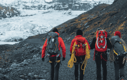 Four hikers with climbing gear and ropes approaching Sólheimajökull glacier in South Iceland