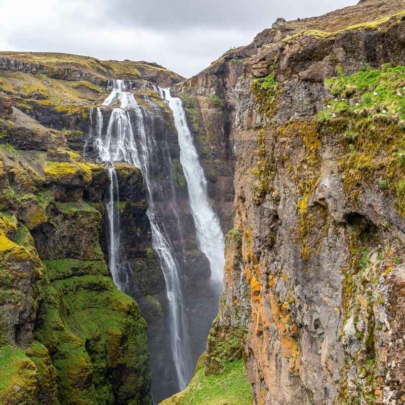 Glymur waterfall cascading down a moss-covered canyon at the end of Hvalfjörður fjord, one of the tallest waterfalls in Iceland.