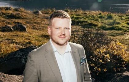 Hilmar Þór Bergmann, COO of Hvammsvík Hot Springs, photographed on the shore of Hvalfjörður fjord with mountains in the background.