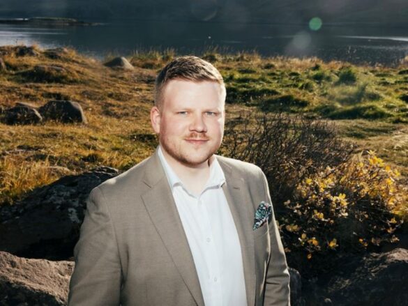 Hilmar Þór Bergmann, COO of Hvammsvík Hot Springs, photographed on the shore of Hvalfjörður fjord with mountains in the background.