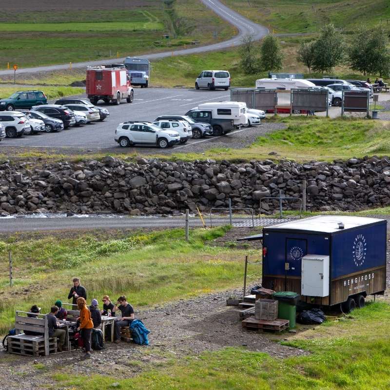 The blue Hengifoss food truck and picnic seating below the Hengifoss parking lot, across the river in Fljótsdalur, East Iceland
